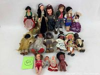 Full lot of 16 assorted vintage dolls arranged in rows showcasing diversity in size, style, and clothing