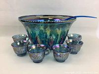 Front view of punch bowl, six cups, and ladle arranged in a semi-circle.