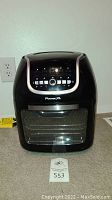 Front view of the black PowerXL Air Fryer Oven with glass door and control panel, showing the included user manuals placed in front.