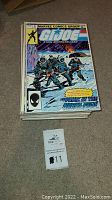 Photo shows a stack of G.I. Joe comic books with the top issue featuring a snowy battle scene cover and Marvel Comics Group branding.