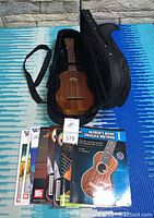Ukulele in open case with instruction books laid in front