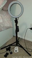 Full view of the LED ring light mounted on tripod stand with phone holder and connected cables.