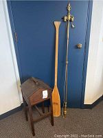 Full view of wooden Priscilla sewing stand, wooden oar, and tall metal floor lamp against wall