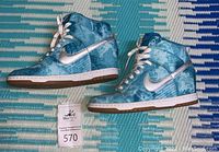 Side view of blue and white Nike Dunk Sky High Clearwater sneakers with white Nike swoosh and laces, showing pattern and overall shoe design.