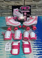 Photo showing pink and white Roller Derby quad skates with pink wheels and toe stops alongside matching pink and white knee, elbow, and wrist protective pads.