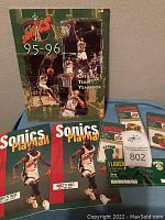 Seattle SuperSonics 1995-96 Official Team Yearbook, two Sonics Playbill programs, temporary tattoos, and ticket stub displayed together