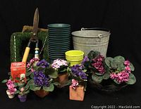 Wide shot of assorted gardening lot showing pots, gardening shears, moss inserts, pest control kit, and various artificial flowers