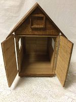 Front view of handcrafted wooden house with both front doors open, showing interior space and wood grain texture