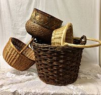 Overview of the five assorted rattan baskets stacked and displayed, showing variety in size, color and handle styles.