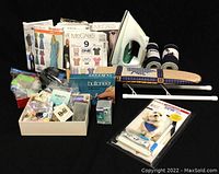 Photo showing the Ultra Glide Elite iron, mini ironing board with patterned cover, multiple sewing accessories in containers, two spools of thread, and the buttoner tool packaging.