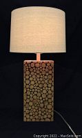 Front view of the table lamp showing the cedar rounds base and fabric drum shade lit up.