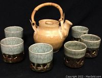 Photo of the stoneware teapot with bamboo handle surrounded by six matching tea cups with crackle glaze and running horse design.