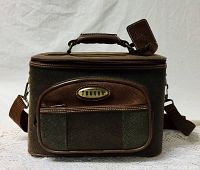 Front view of brown textured and smooth leather-like travel bag with Jaguar metal nameplate, front zippered pocket, top handle with padded grip and attached key holder tag.