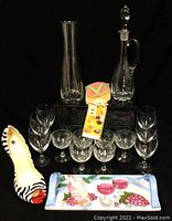 Full view of all lot items: carafe, decanter, two sets of glasses, heel-shaped bottle holder, coasters, charcuterie board underneath