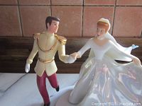 Close-up image of Cinderella and Prince Charming holding hands in wedding attire figurine with fine detail and glossy finish.