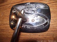 Photo shows the back of a rectangular chrome Harley Davidson motorcycle mirror with attached mounting arm. The back of the mirror has an engraved eagle and the text 'Live to Ride Ride to Live' and 'Harley-Davidson'.