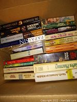 Books stacked in cardboard box showing spines of fiction titles including John Grisham's The Last Juror and The Street Rose, Garry Wills, and others