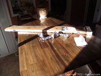 Live edge wood mantel shelf laid flat on table with black pipefitter mounting hardware and packaging shown.