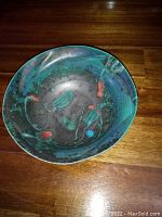 Top view of first pottery bowl showing mottled green and blue glaze with red accents inside, irregular organic shape.