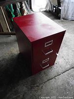 Closed red metal filing cabinet with two drawers and a visible lock.