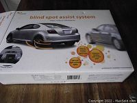 Packaging box showing blind spot assist system graphic with features including object detection in blind spot and warning lights.