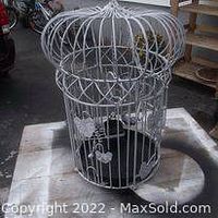 View of the vintage solid metal bird cage showing dome-shaped top, decorative metal elements on bars, black base, and hanging hook.
