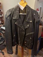 Black leather motorcycle jacket showing classic biker style with zipper, snap buttons, and epaulets.