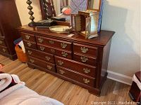 Front view of the solid wood dresser with 7 drawers, decorated with brass handles, and items on top, including a jewelry box and decorative objects.