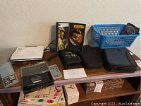 Lot contents on table showing Nintendo DS Lite console, game cases, carrying cases, and Coby portable DVD player