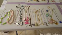 Overview of all necklaces and rings included in the lot on display on table