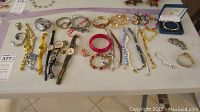 Full view of assorted jewelry including bracelets, rings, necklaces, and watches displayed on table