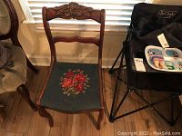 Full view of hand carved mahogany chair showing carved floral motif on backrest, wooden frame, and embroidered floral seat upholstery.