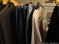 Photo showing six youth clothing items hanging, including three pairs of jeans and three tops.