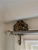 Close-up of ornate metal wall mount holding silver curtain rod with rounded end cap.