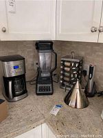 Overview of coffee maker, blender, spice rack, tea kettle and wine opener on countertop