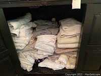 Shelves with folded linens showing towels, blankets, and bedding in neutral colors.