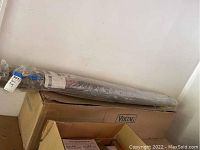 Rolled and packaged woven floor rug placed on top of a box.