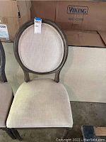 Restoration Hardware dining chair with round back, beige upholstery, and dark wooden frame.