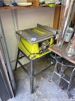 Full view of a yellow Ryobi table saw mounted on a black metal stand.