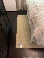 Sisal rug placed next to bed and nightstand showing weave texture and beige color.