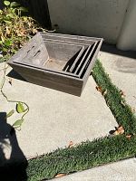 Four nested wooden trays stacked outdoor on concrete with some leaves around. Trays have a dark rustic finish and some dirt inside.