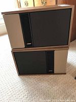 Pair of Bose bookshelf speakers stacked with front black grille and wood veneer sides visible.
