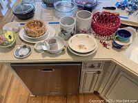 Overview of all ceramic bowls, canisters, baskets, and dishes laid out on a kitchen counter.