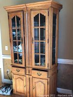 Front view of two matching Thomasville wooden cabinets with glass doors revealing glass shelves inside, drawers and wooden storage doors below.