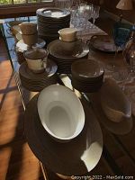 Overall view of 85 piece Sango Phoenicia china dinnerware set including plates, bowls, cups, saucers, and serving pieces.