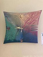 Front view of a square wooden wall clock with a colorful artistic finish and a sun motif at the top center.