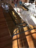 Top view of the clear beveled glass dining table with various glassware placed on top, showing the thickness and transparency of the glass.