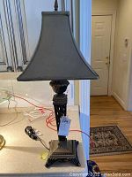 Full view of the metal table lamp showing ornate dark metal base and square fabric shade, about 29 inches tall. Power cord and plug visible but lamp is untested.