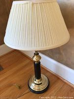 Full view of the lamp showing cream pleated fabric shade and brass plus black marble base.