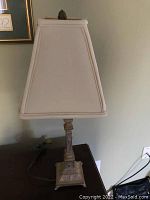 Full view of metal table lamp with beige fabric shade, showing overall appearance and lampshade shape